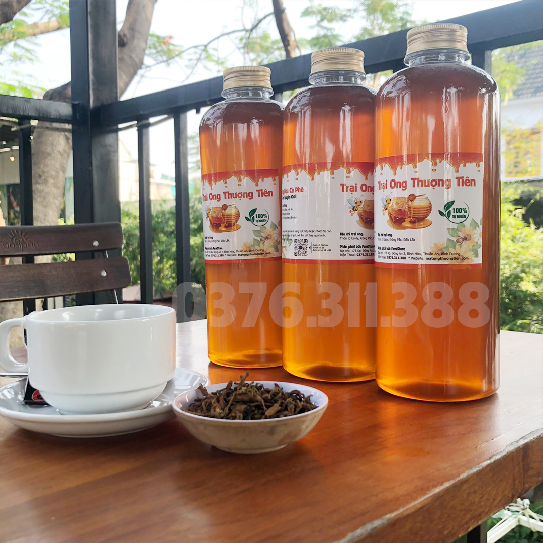 Khách hàng thưởng thức trà mật ong hoa nhãn và mật ong hoa cà phê tại nhà, không gian ấm cúng, ly trà vàng óng ánh, mang lại cảm giác thư giãn và tận hưởng hương vị tự nhiên.