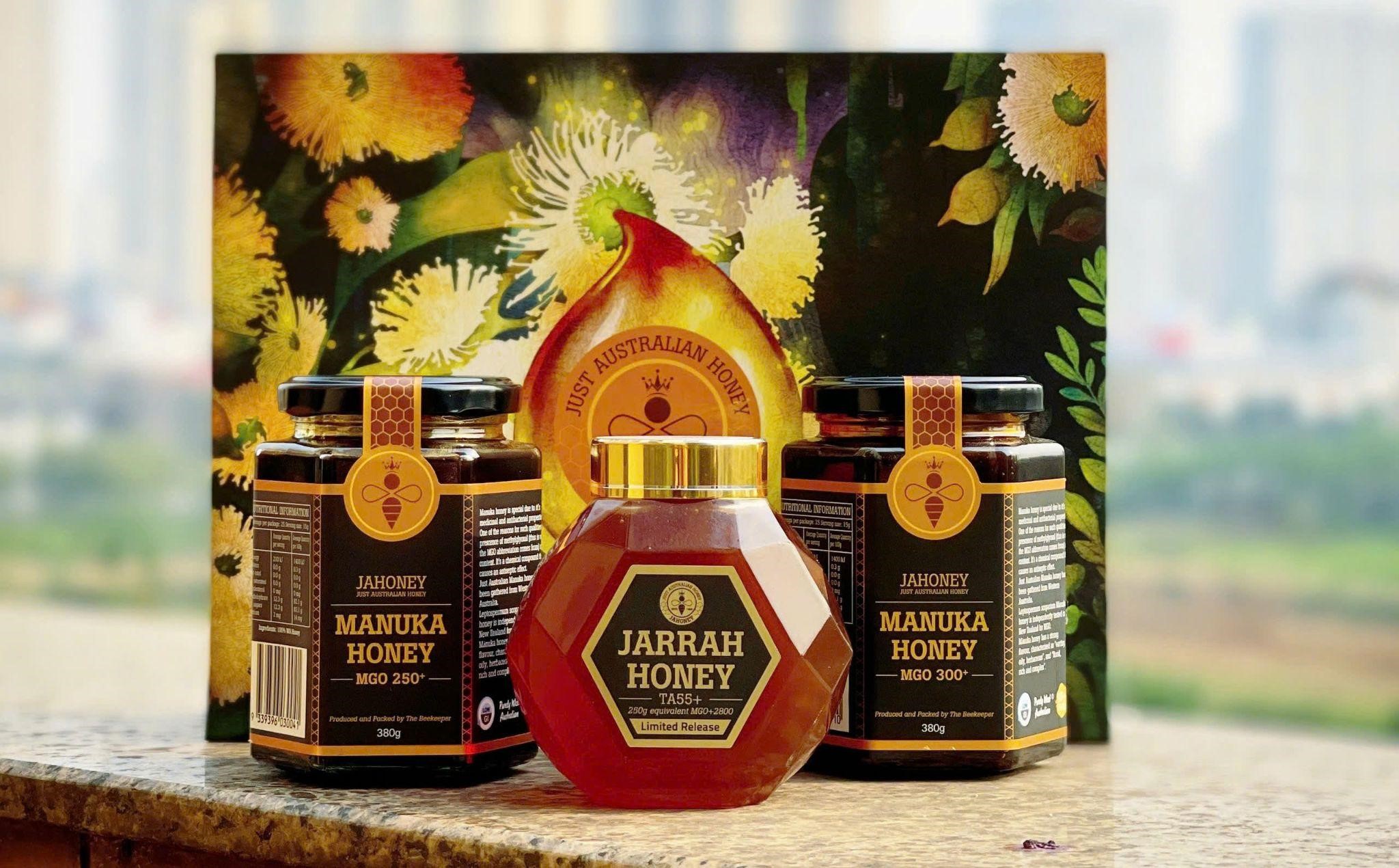 Lọ mật ong Manuka và lọ mật ong hoa nhãn Việt Nam đặt cạnh nhau trên bàn gỗ, minh họa sự khác biệt giữa hai loại mật ong nổi tiếng