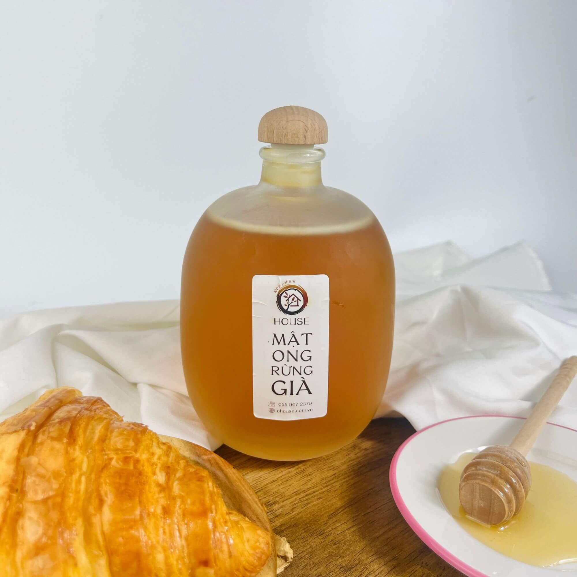 Lọ mật ong rừng vàng óng, cạnh tổ ong và hoa rừng